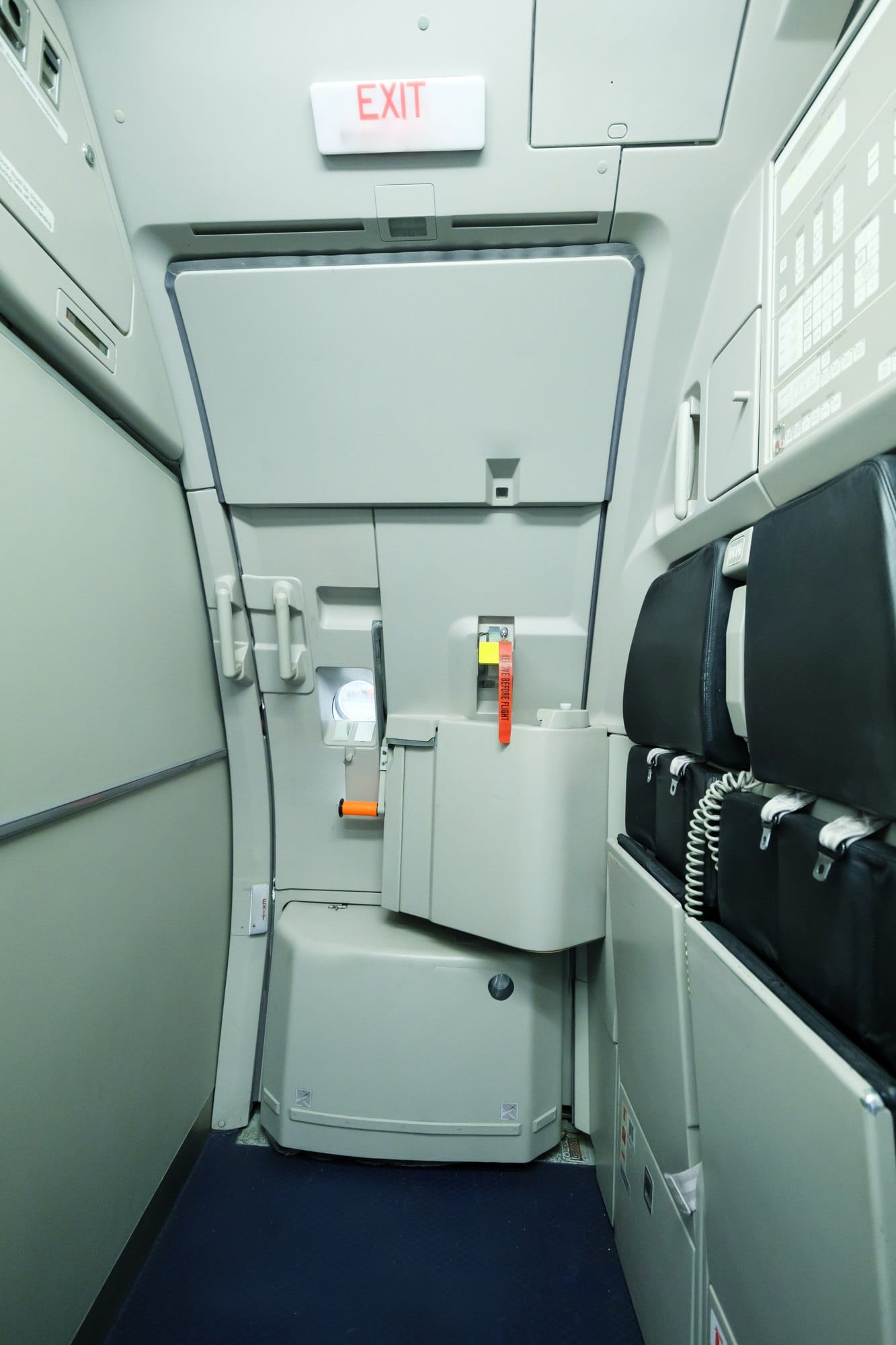Interior view of a commercial airplane exit door area showing safety equipment