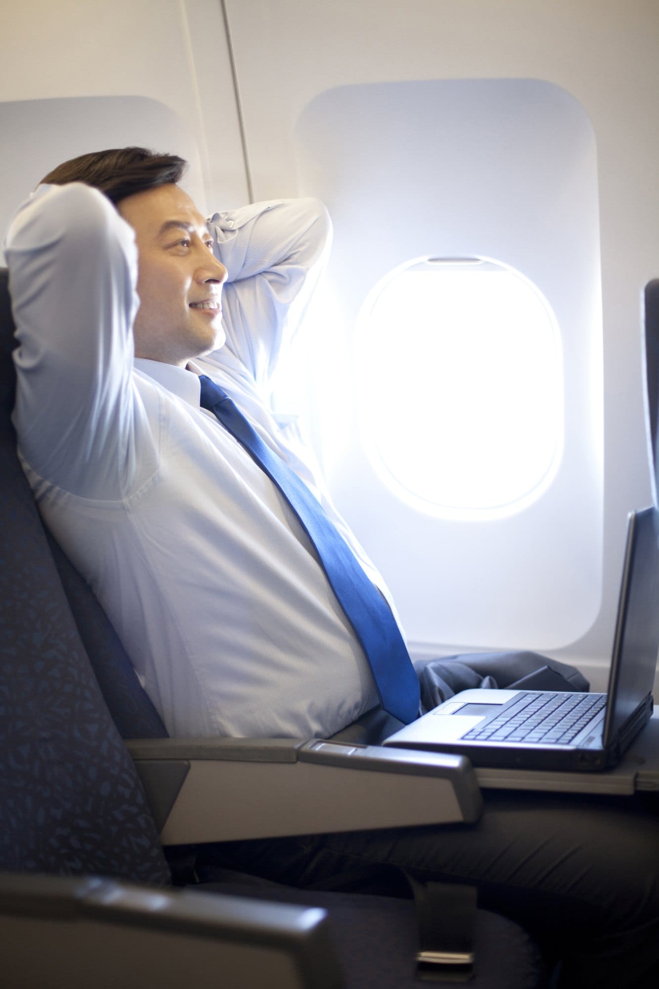 Man Relaxing on Airplane with Laptop