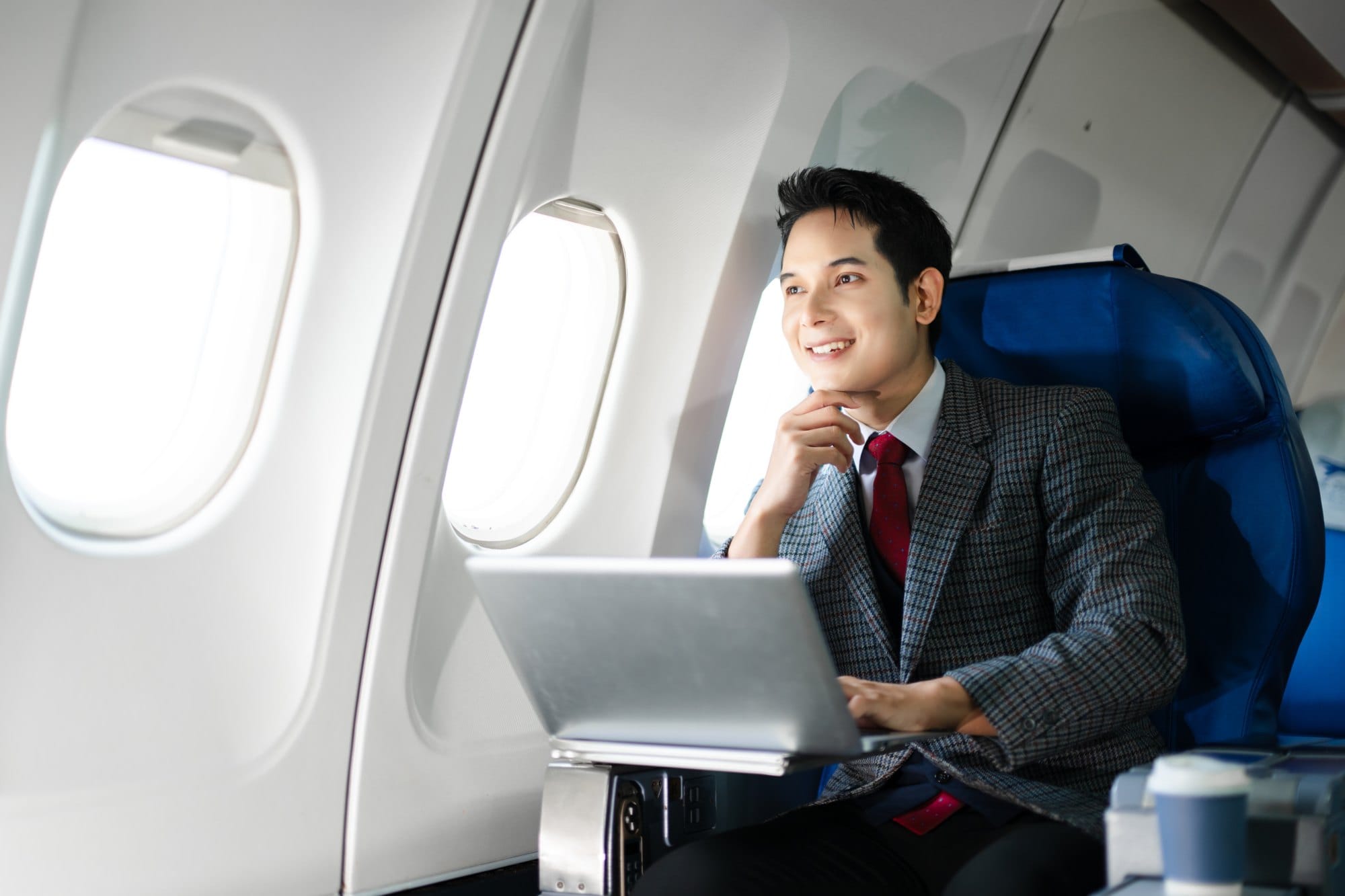 Man Working On Laptop In Airplane Seat
