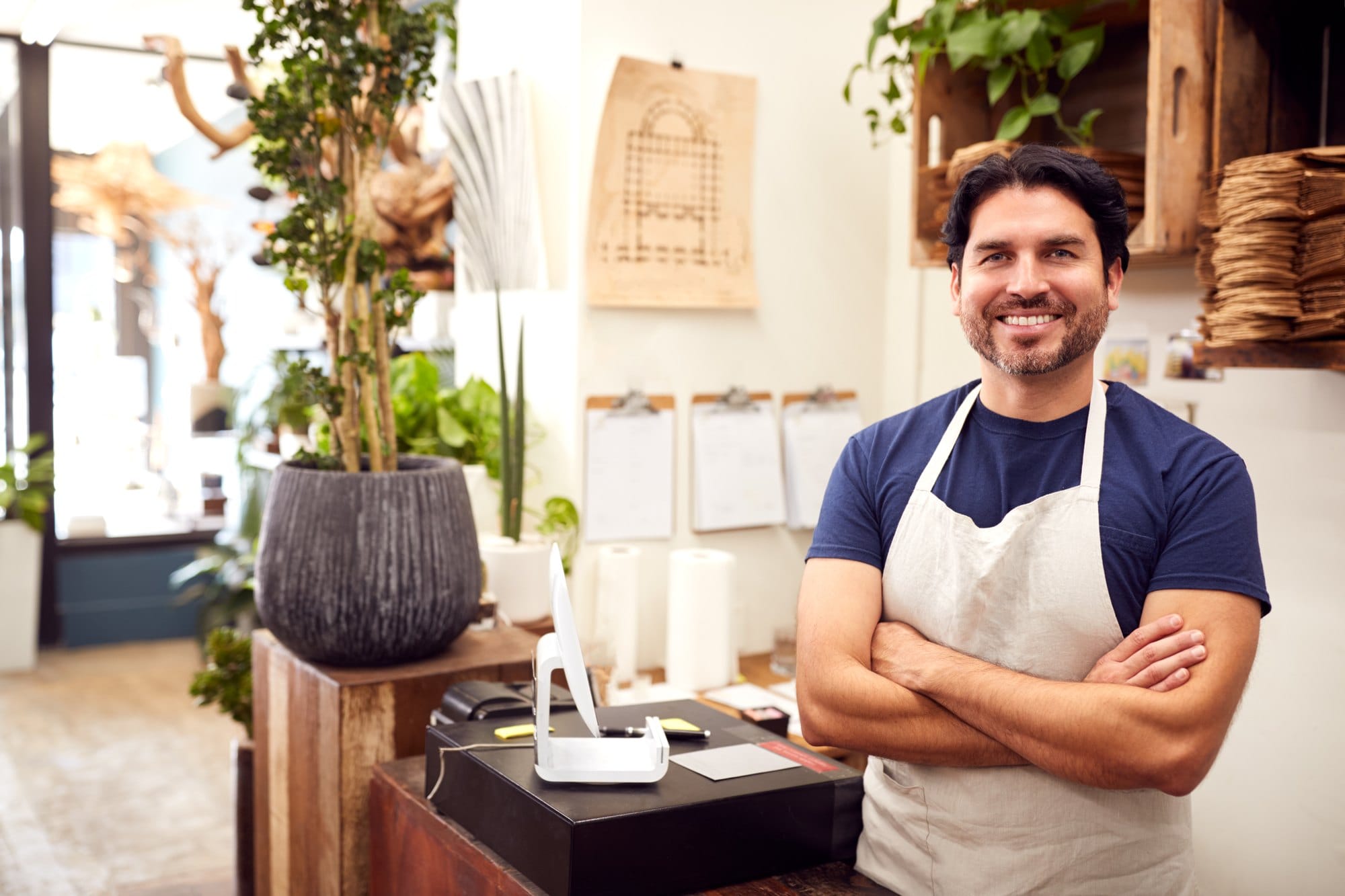 Portrait Of Smiling Male Sales Assistant Standing By Sales Desk Of Florists Store