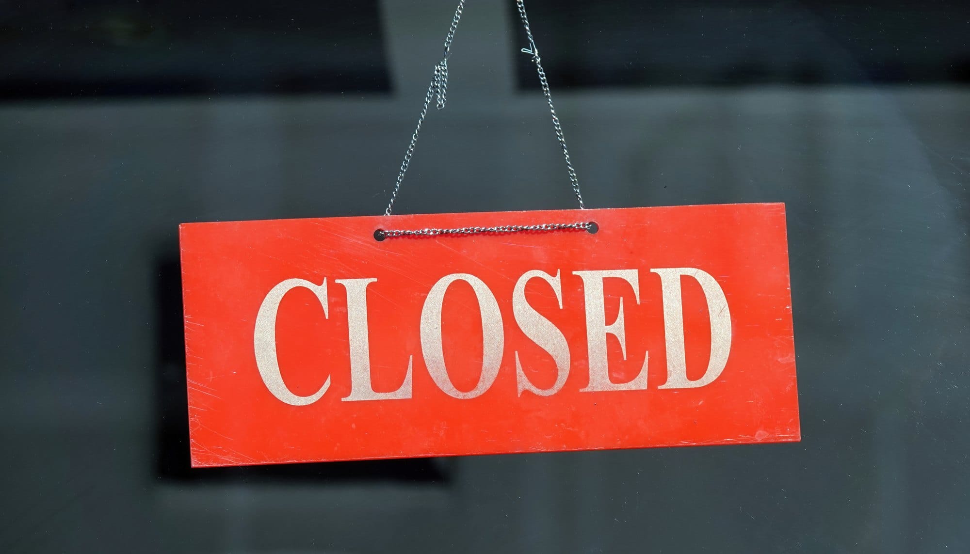 Red Sign Reads Closed Hanging in Window