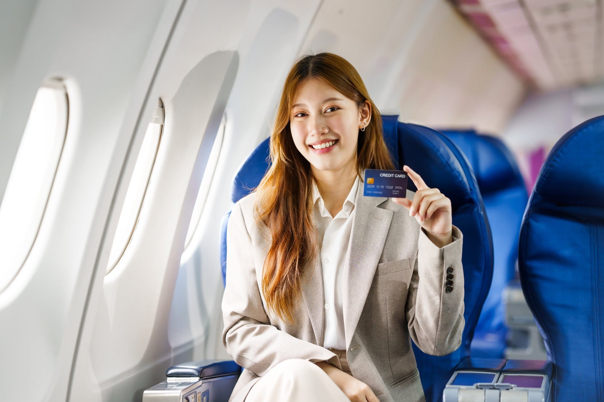 Smiling Woman with Credit Card on an Airplane