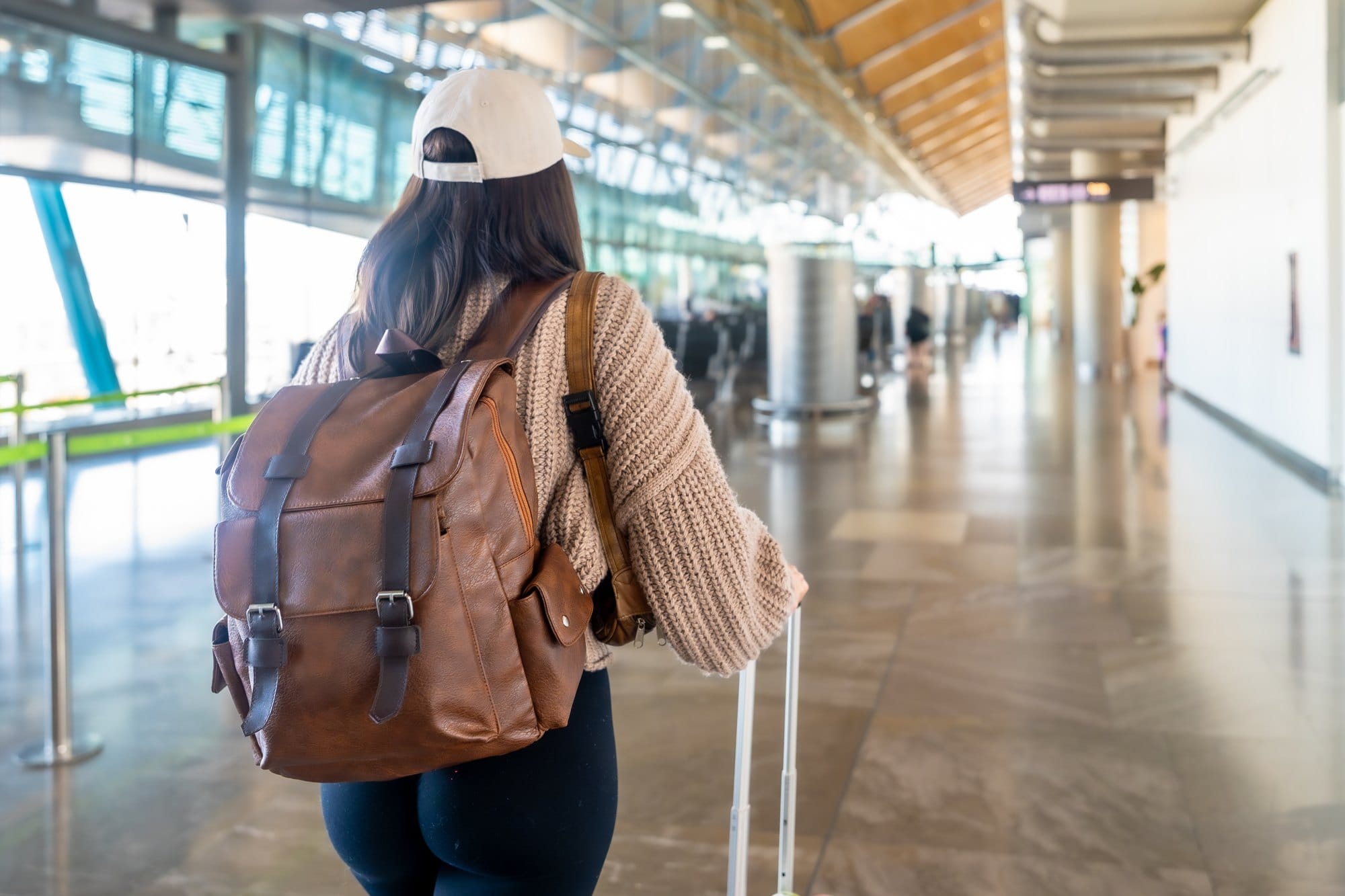 Woman traveling through airport terminal with backpack and luggage