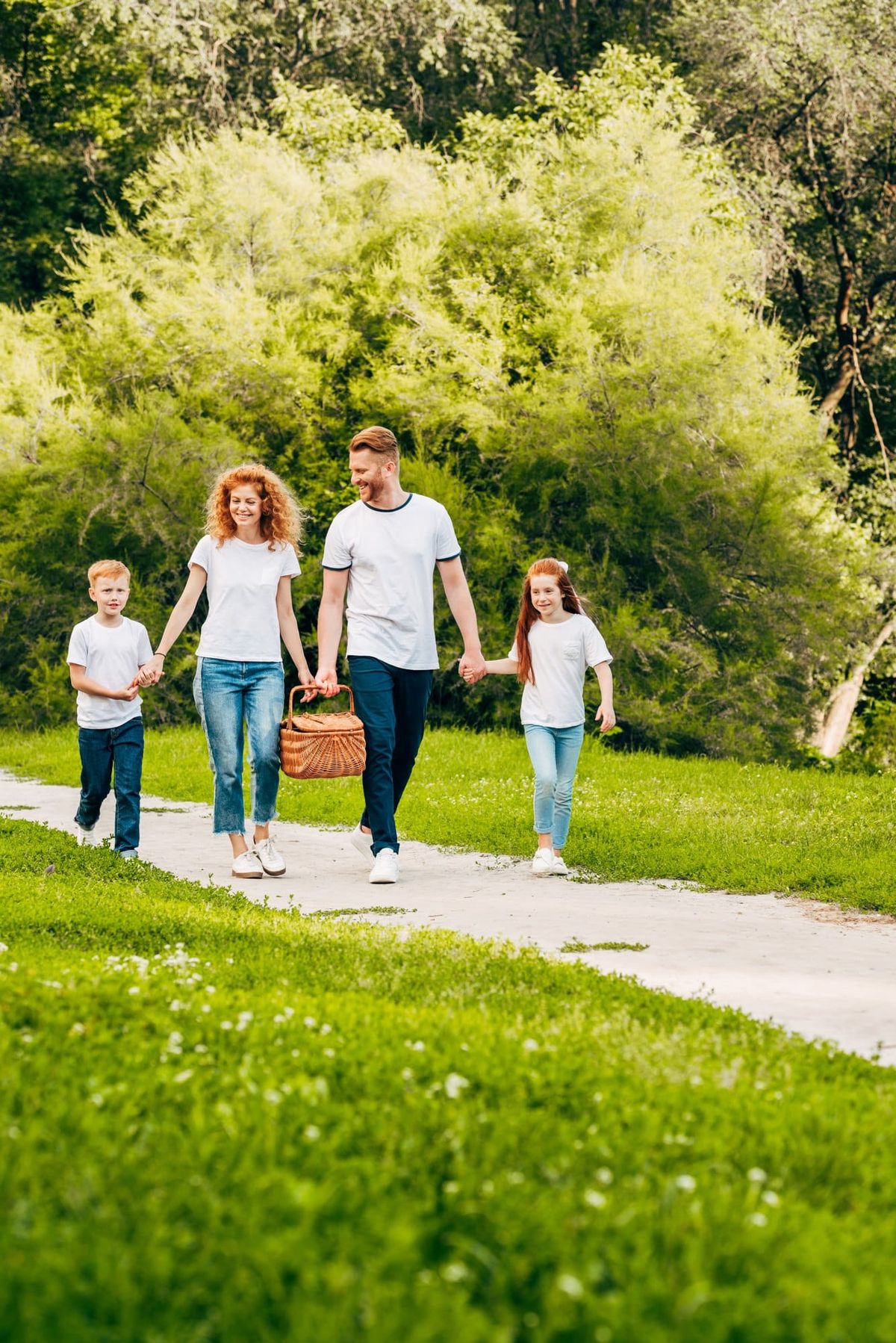 Happy family holding hands and walking with picnic basket at park