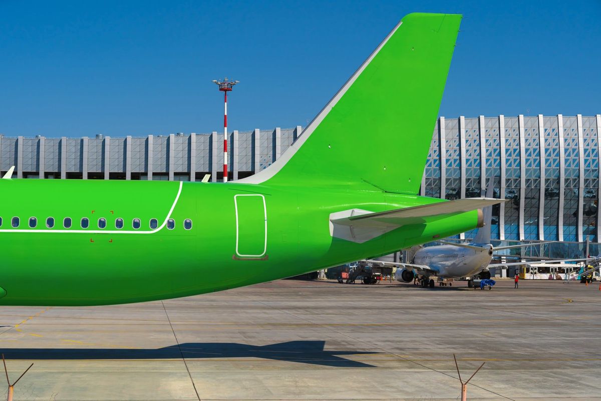 Green passenger airplane at the airport on sunny day