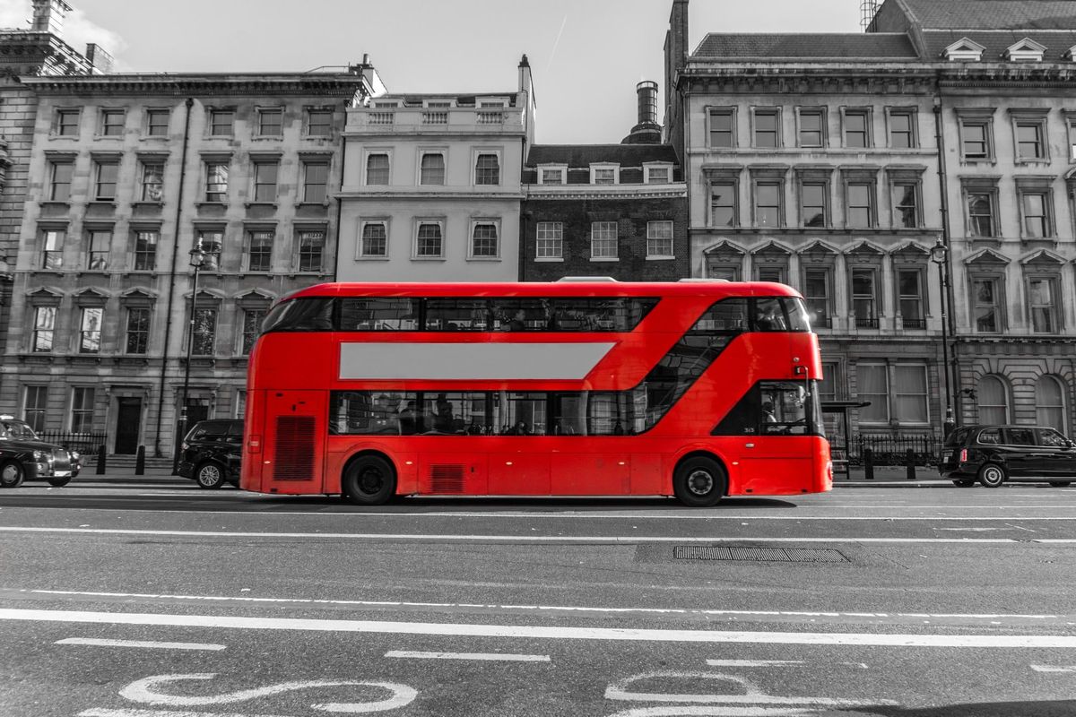 RED Double Decker Bus driving down city street - Red Color in Black and White