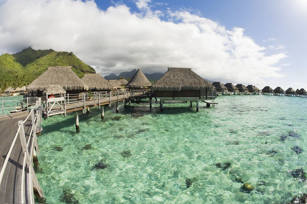 Tropical Overwater Bungalows With Thatch Roofs in Turquoise Sea