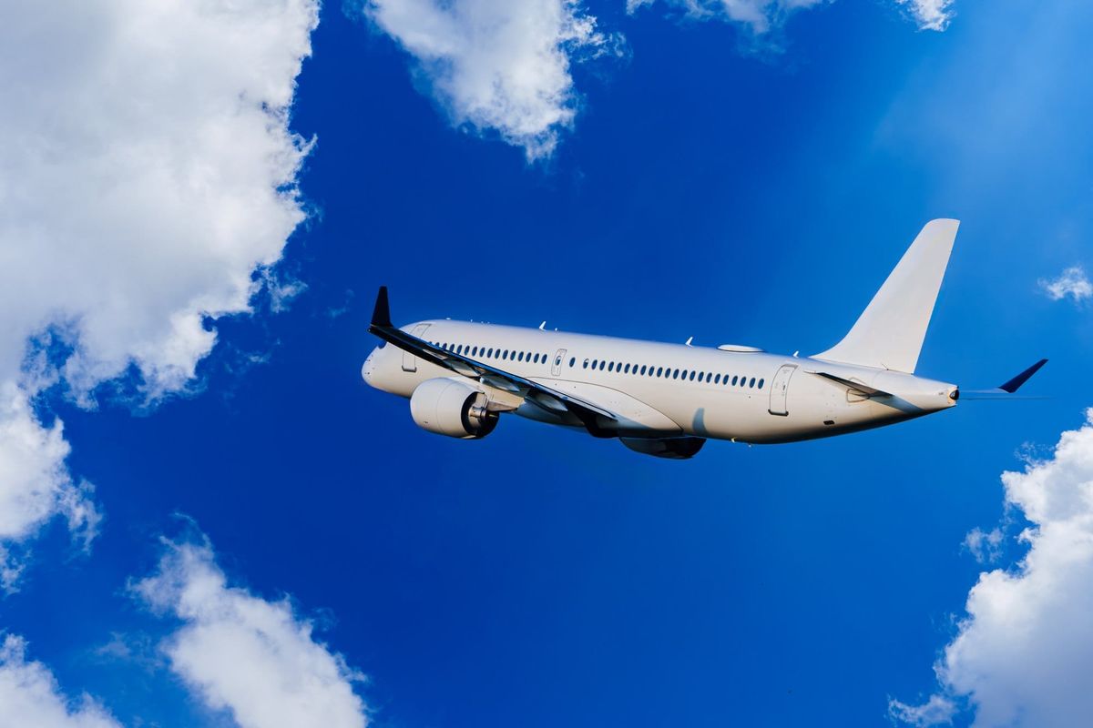 Passenger Airplane Flying Through Blue Sky With Clouds