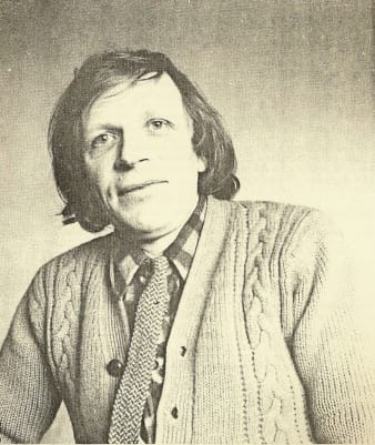 monochrome photo of a middle-aged man. He looks--I feel mean for saying this--sort of like his face is a rubber mask stretched over his actual face. Yet his awkward expression, mop-like haircut and cable-knit sweater give him an endearing appearance overall