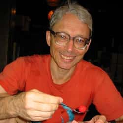 Photo of a smiling, grey-haired man, holding a spoon that contains, maybe, a raspberry? Hard to say. He looks awkward and non-photogenic but kind and trustworthy. That's what I reckon anyway.