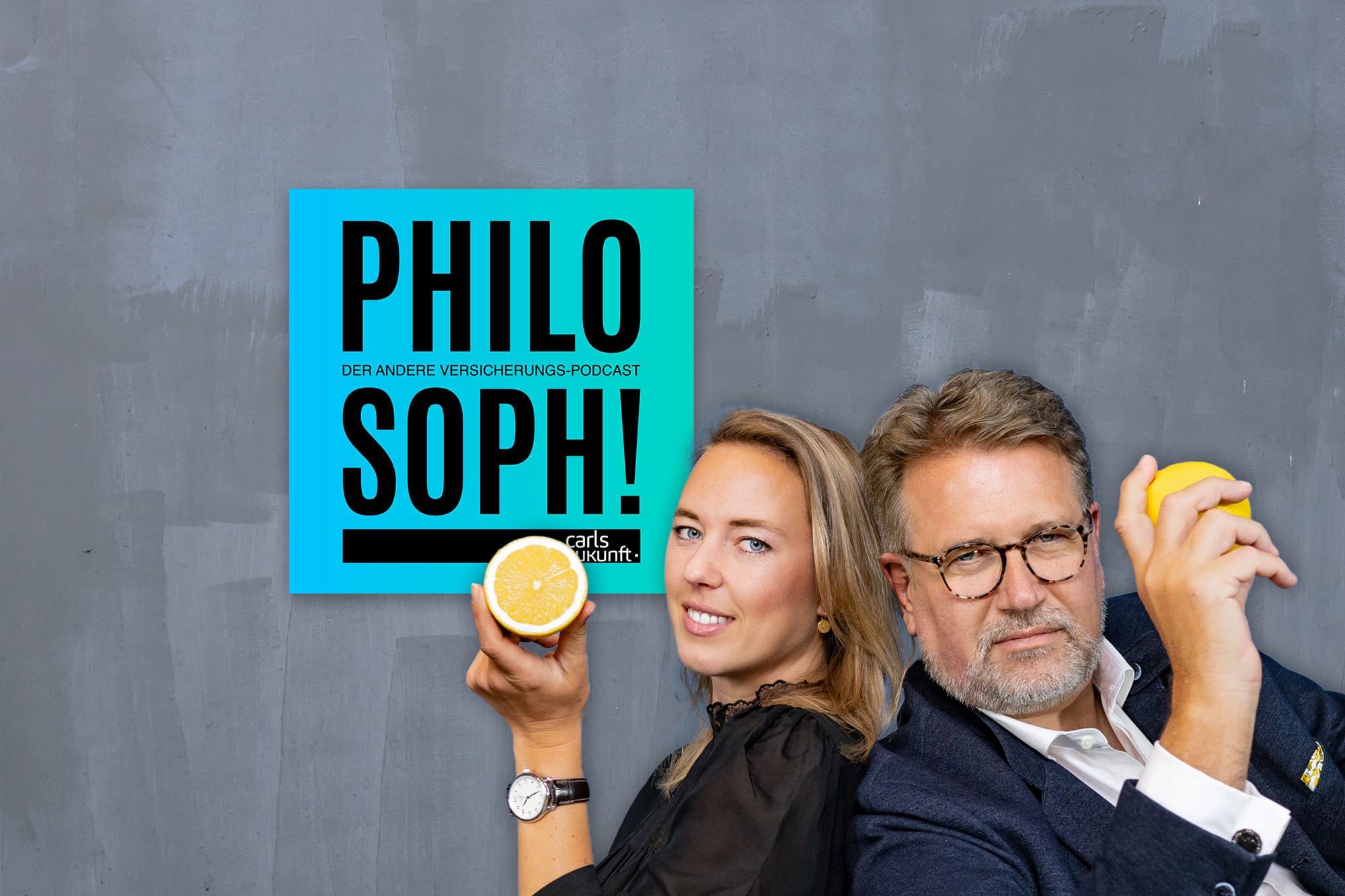 Podcast „Philosoph!“ mit Martin Gräfer und Anna Kuhns: Zwei Personen vor grauer Wand halten Zitronen in der Hand.