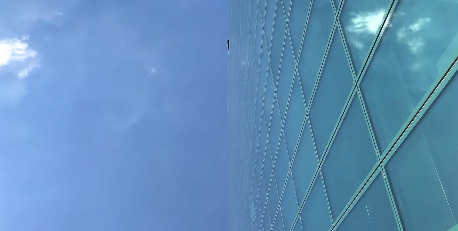 Die Glasfassade eines Hochhauses scheint im blauen Himmel zu verschwimmen