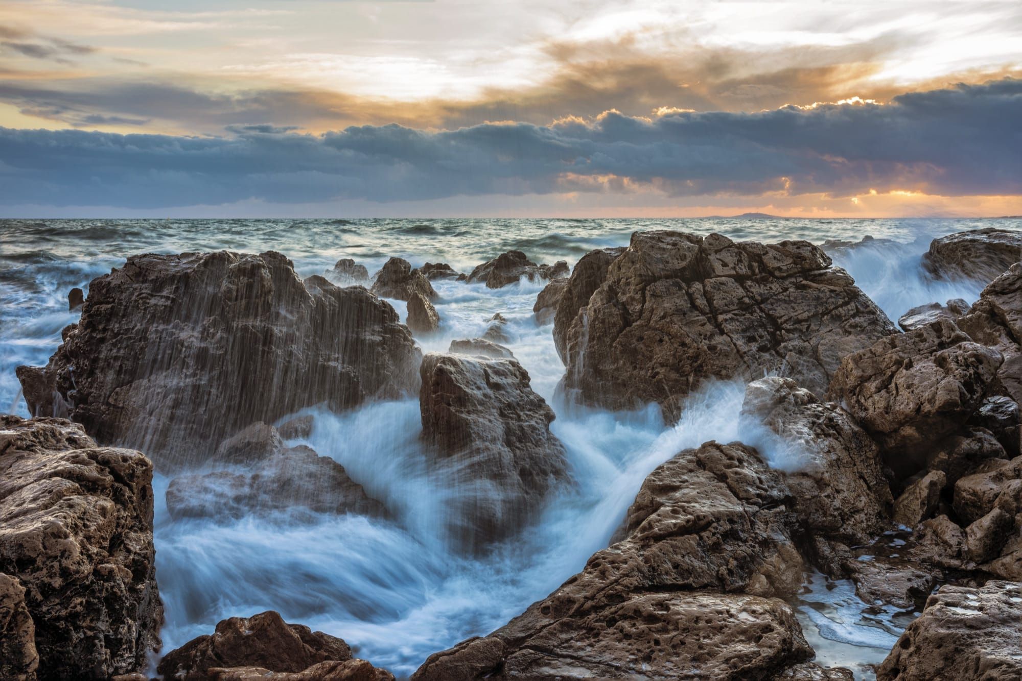 Valuri puternice ale oceanului lovind stânci de coastă la apus