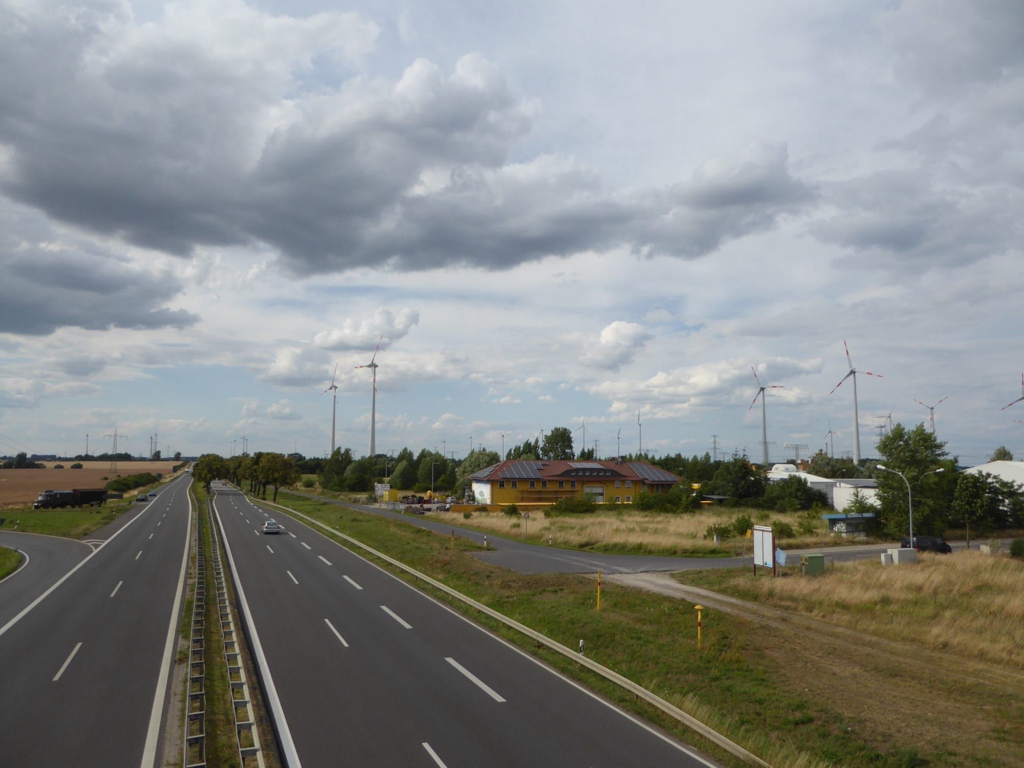 Turbine eoliene și panouri solare pe un acoperiș, lângă o șosea din Germania