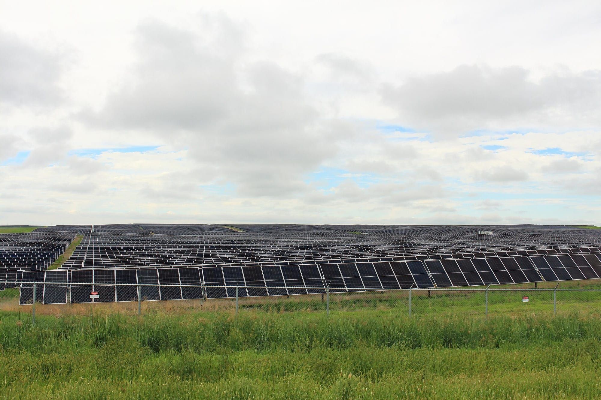 Parc fotovoltaic mare, cu rânduri de panouri solare sub cer înnorat