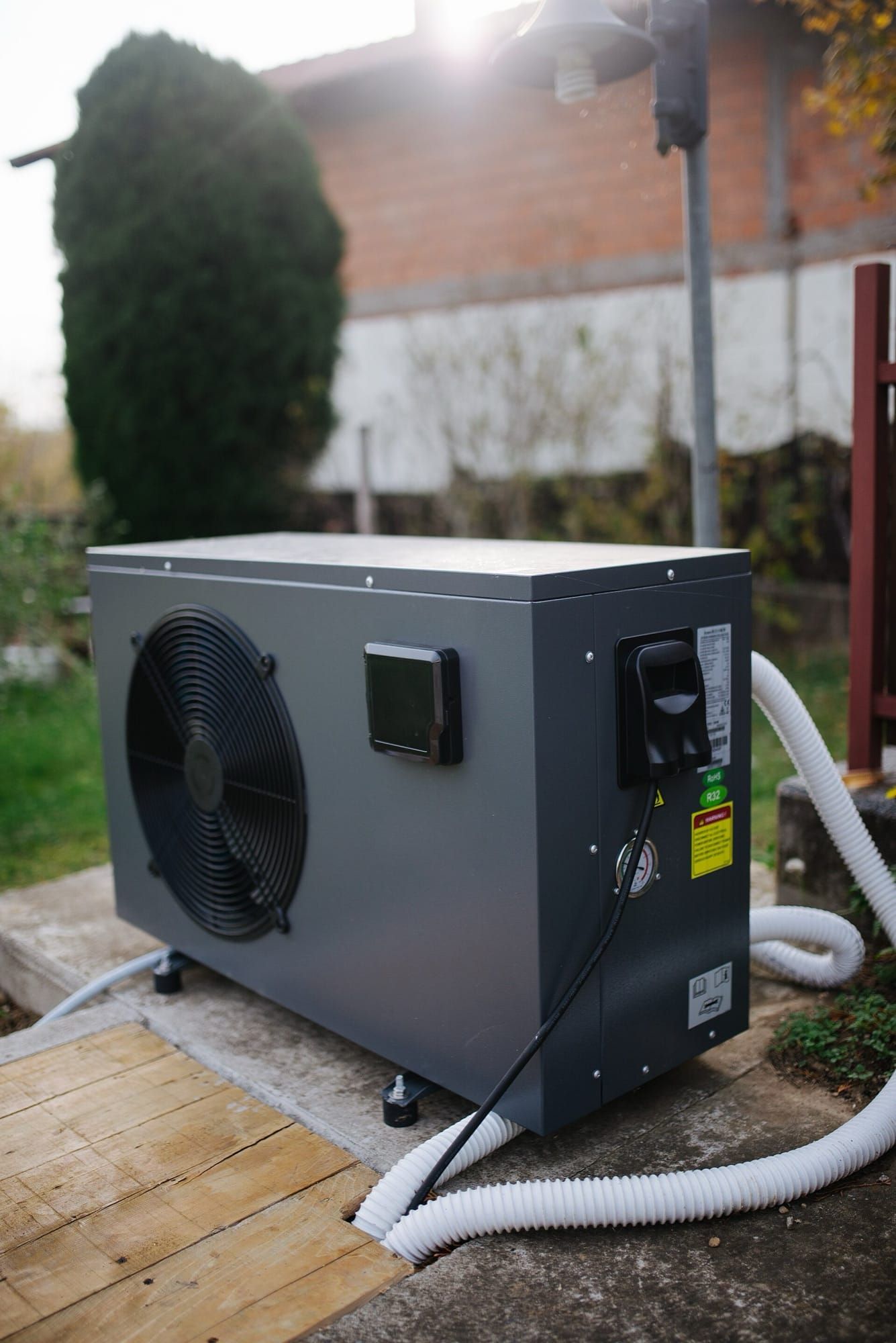 Pompă de căldură modernă instalată în curtea unei case