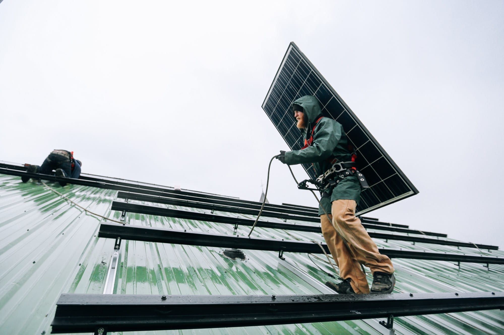 Muncitor instalând un panou solar pe acoperișul unei clădiri