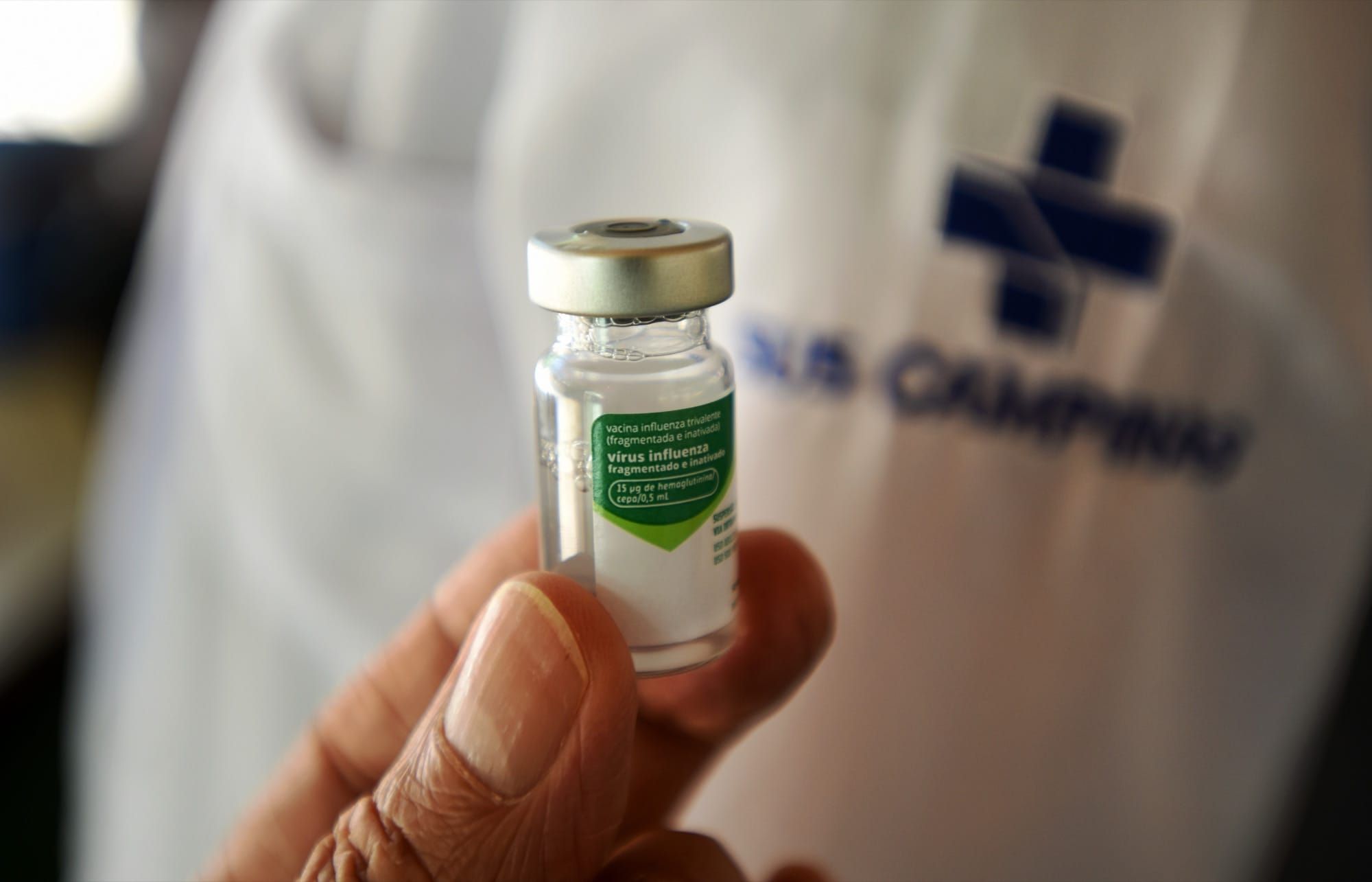 Un cadru medical ține în mână un flacon de vaccin antigripal