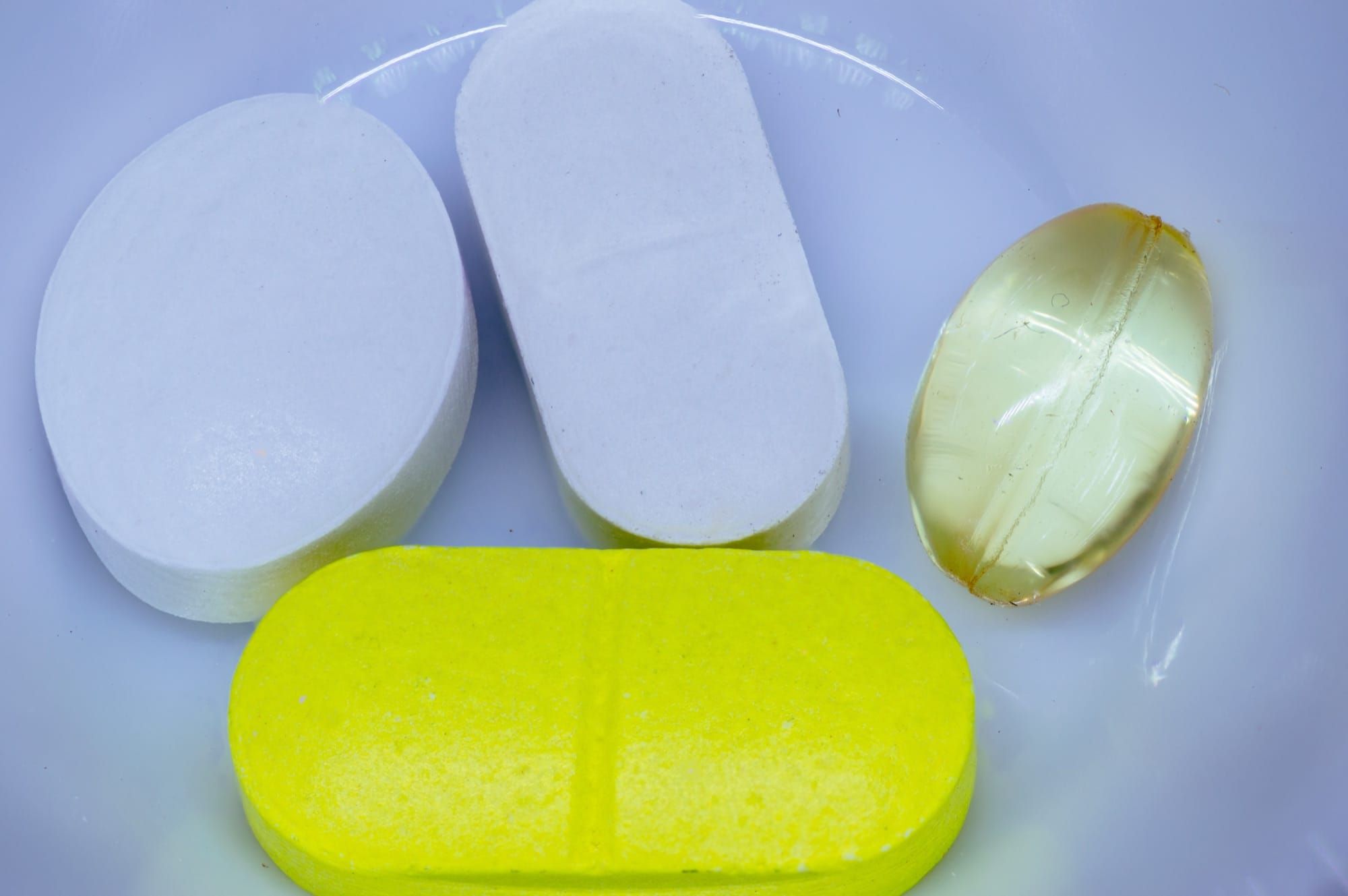 Comprimate medicamentoase albe și galbene pe fundal alb