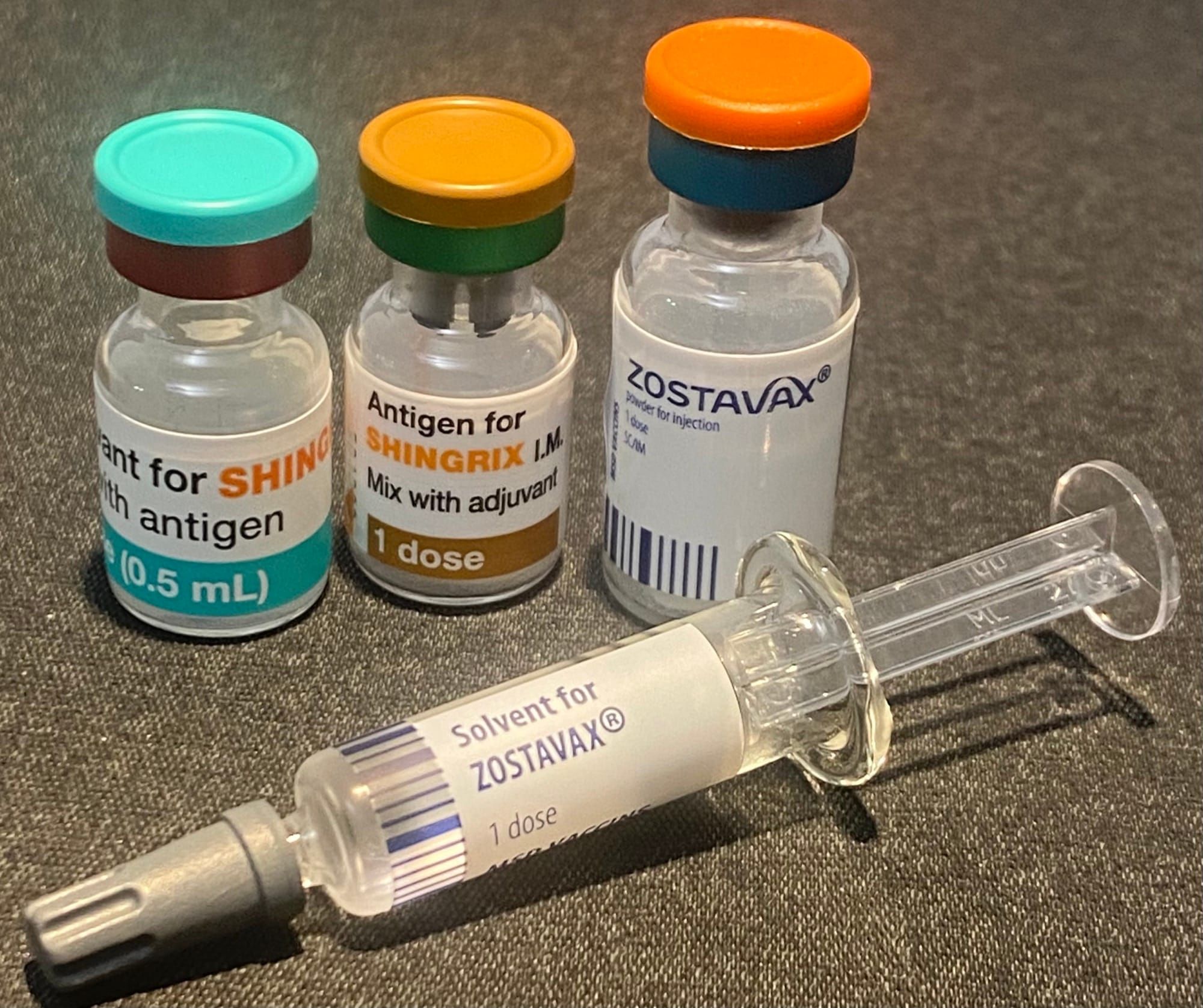 Fiole cu vaccinurile Shingrix și Zostavax contra zonei zoster, alături de o seringă