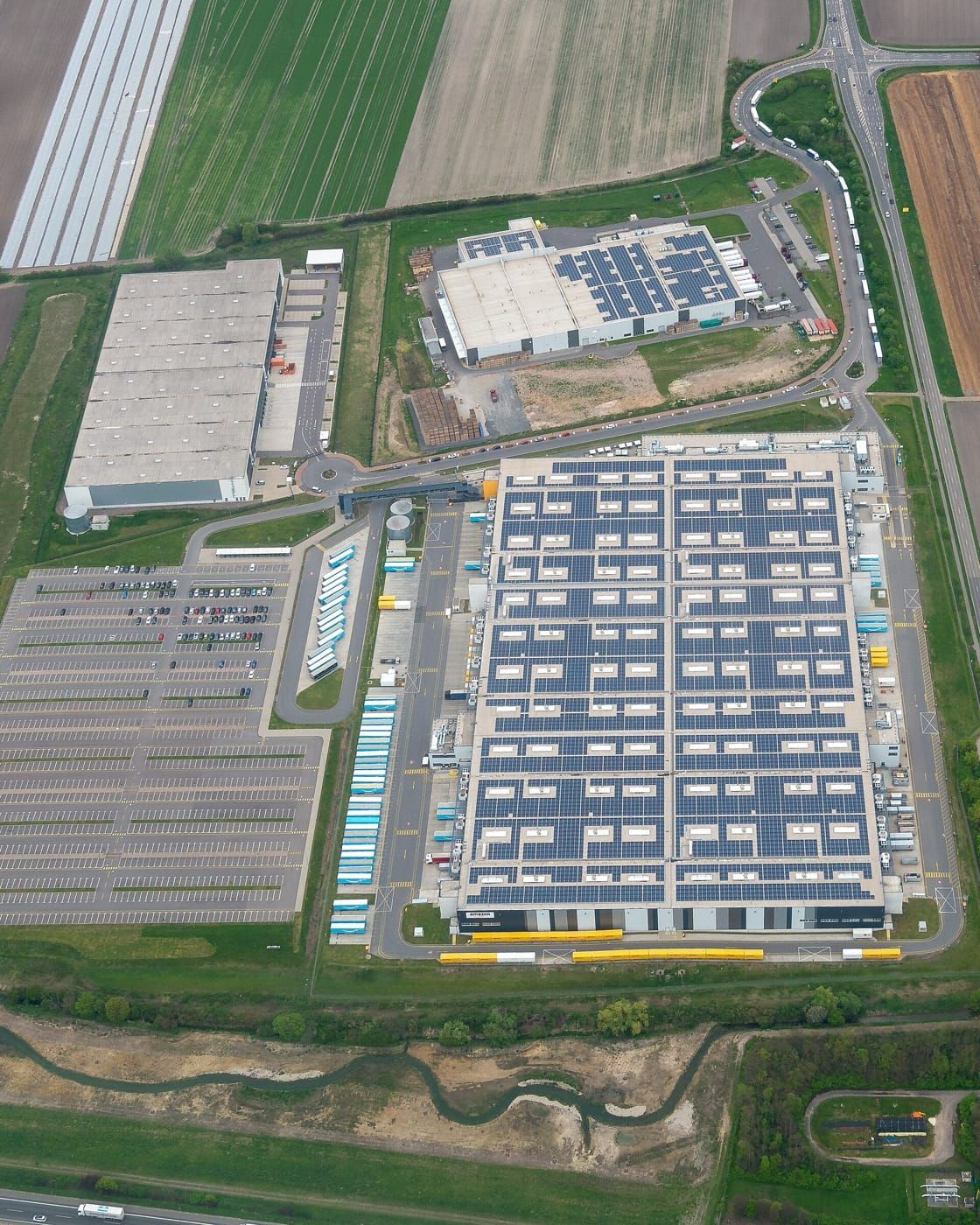 Vedere aeriană a unui acoperiș de depozit acoperit aproape integral cu panouri solare
