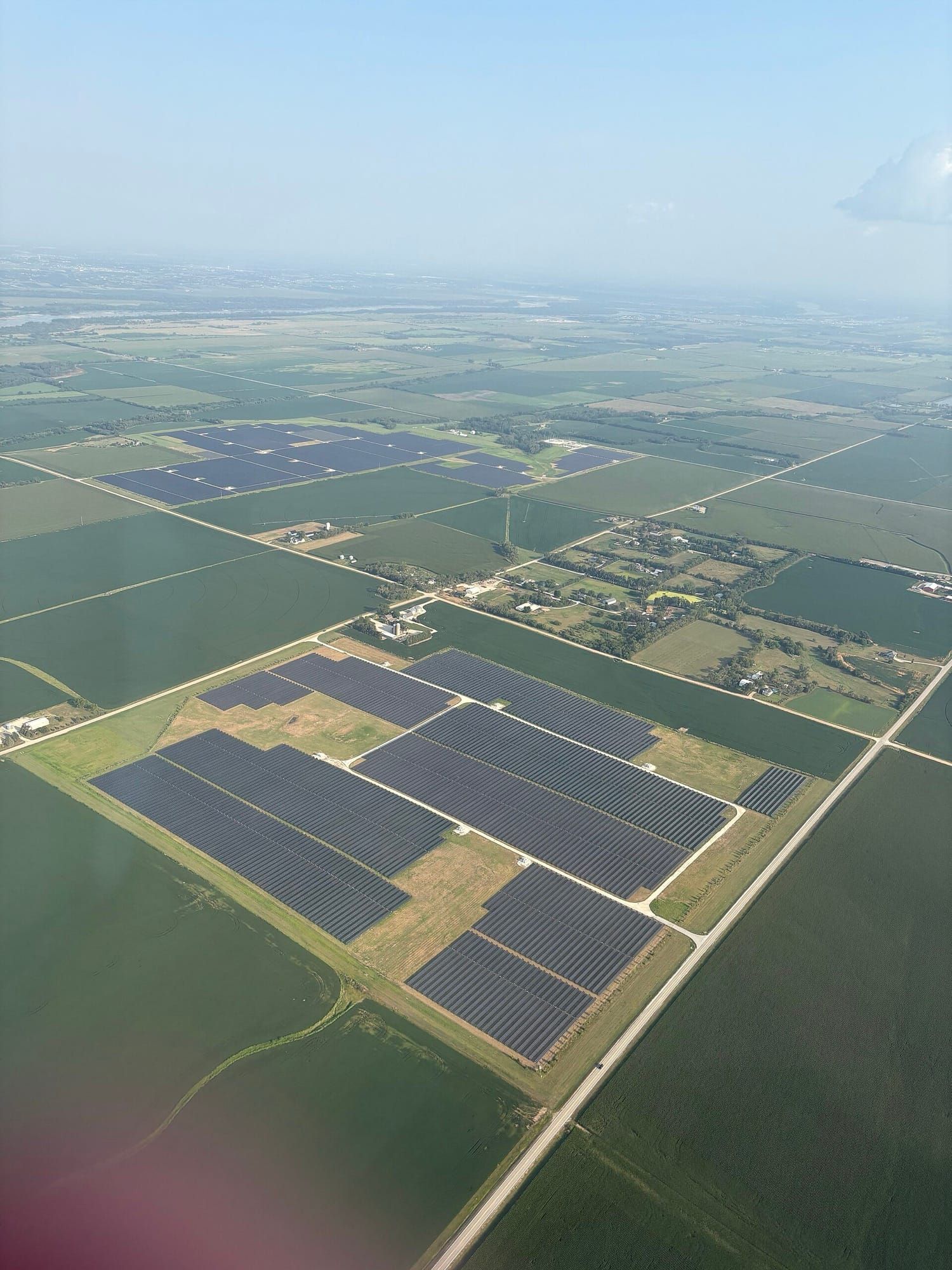 Vedere aeriană a unui parc fotovoltaic întins pe câmpuri agricole