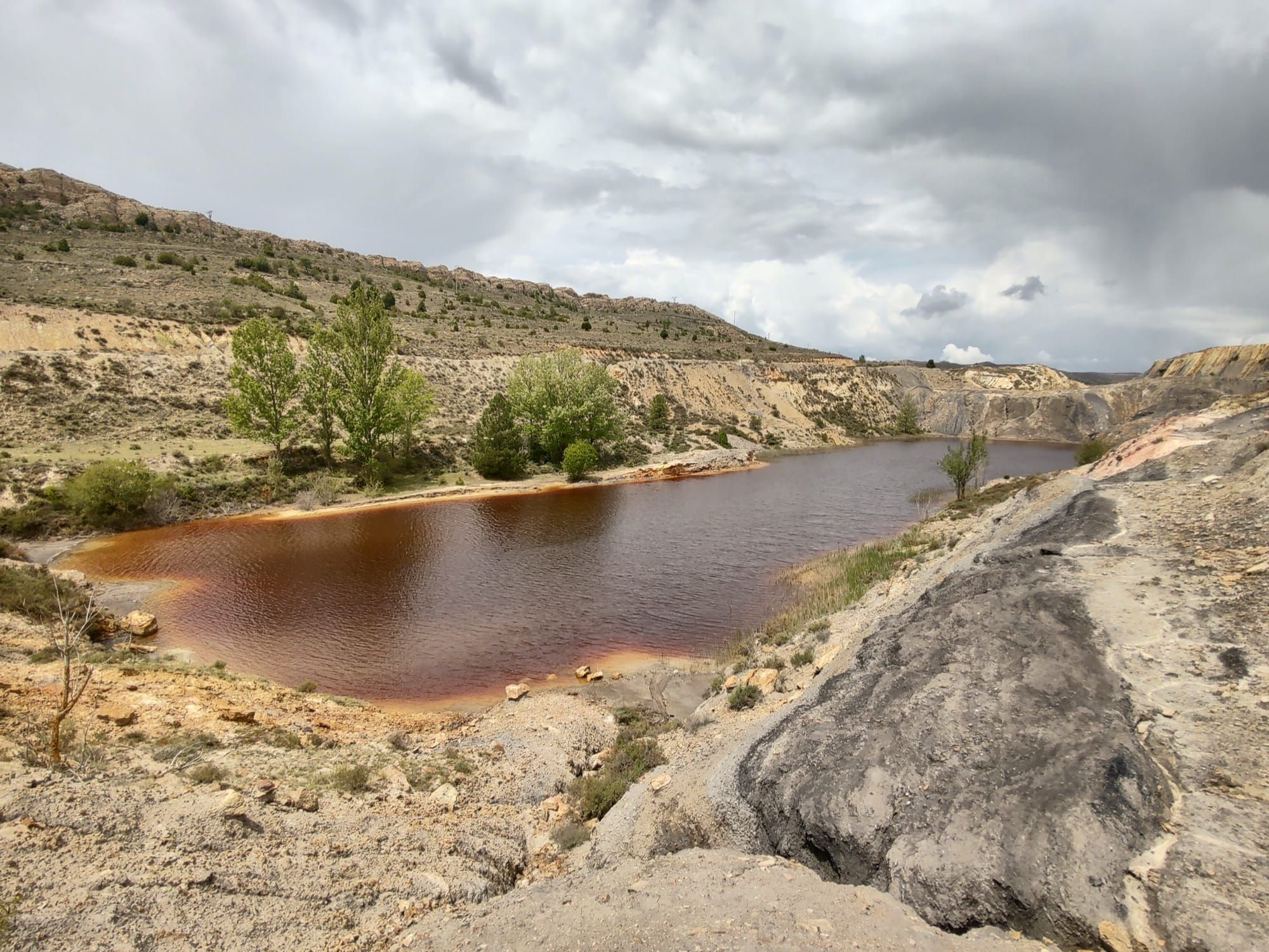 Iaz cu apă contaminată de minerit, colorată roșcat de conținutul mineral ridicat