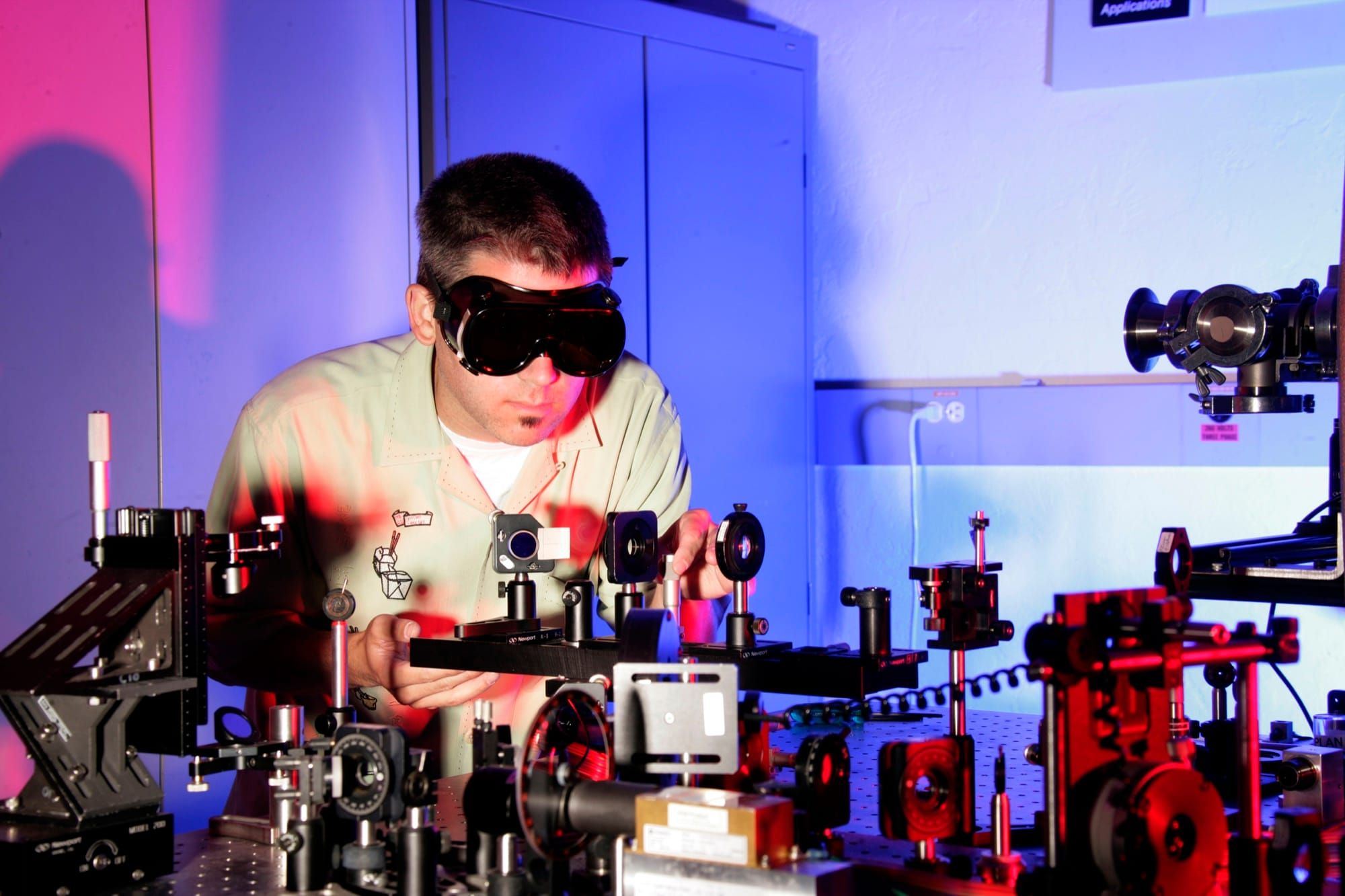 Cercetător lucrează la un montaj optic cu laser, imagine reprezentativă a unui laborator de fotonică
