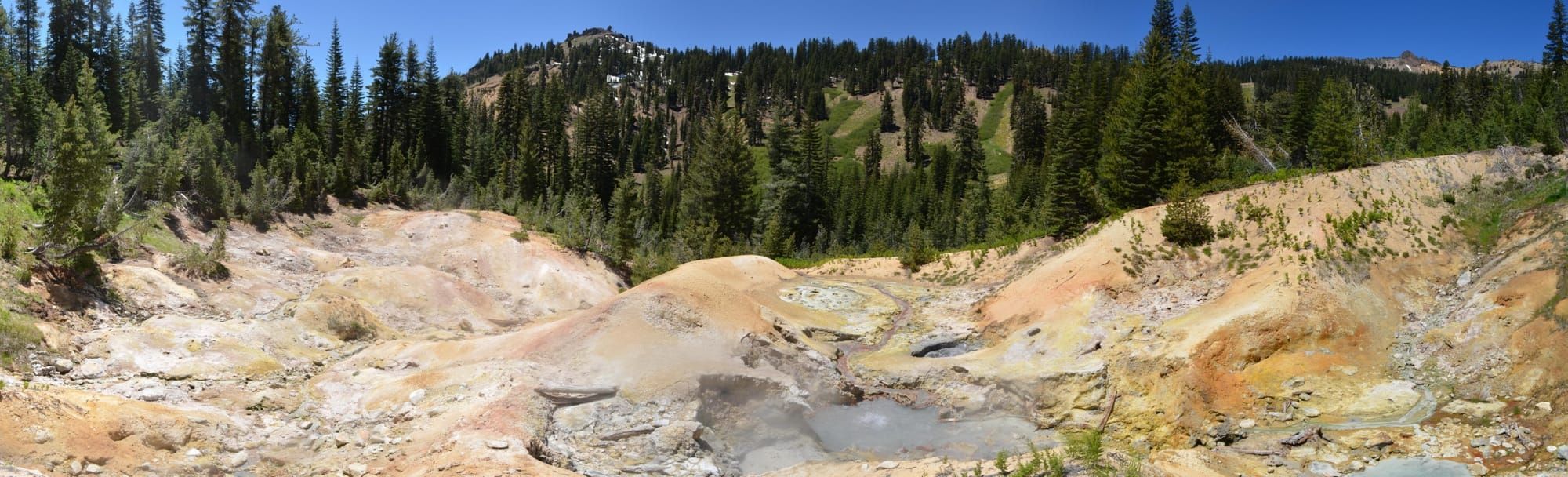 Peisaj cu izvoare termale și fumarole în Lassen Volcanic National Park, înconjurat de pădure de conifere
