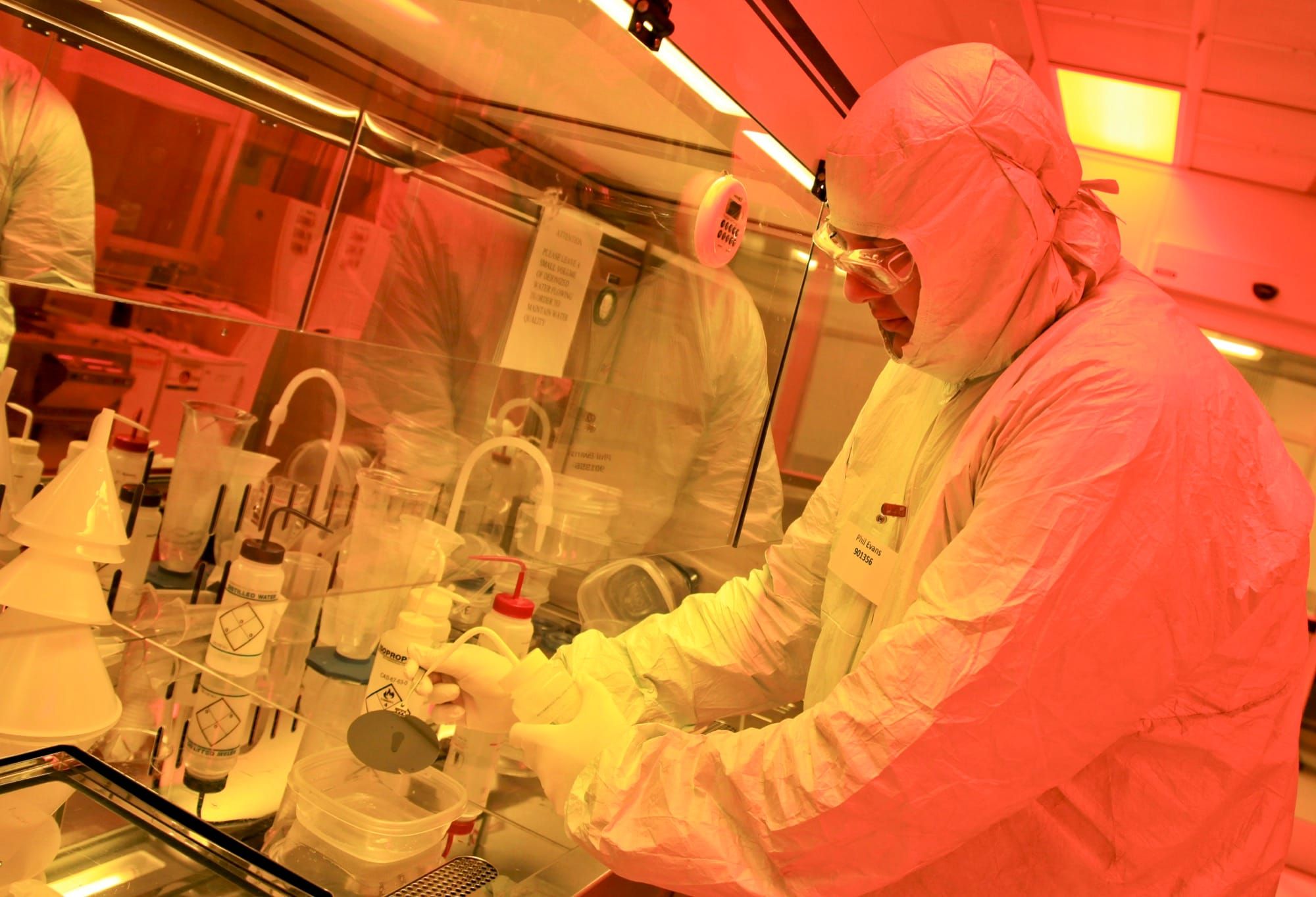 Cercetător în echipament de protecție lucrează într-o cameră curată de nanofabricație (imagine ilustrativă de laborator)