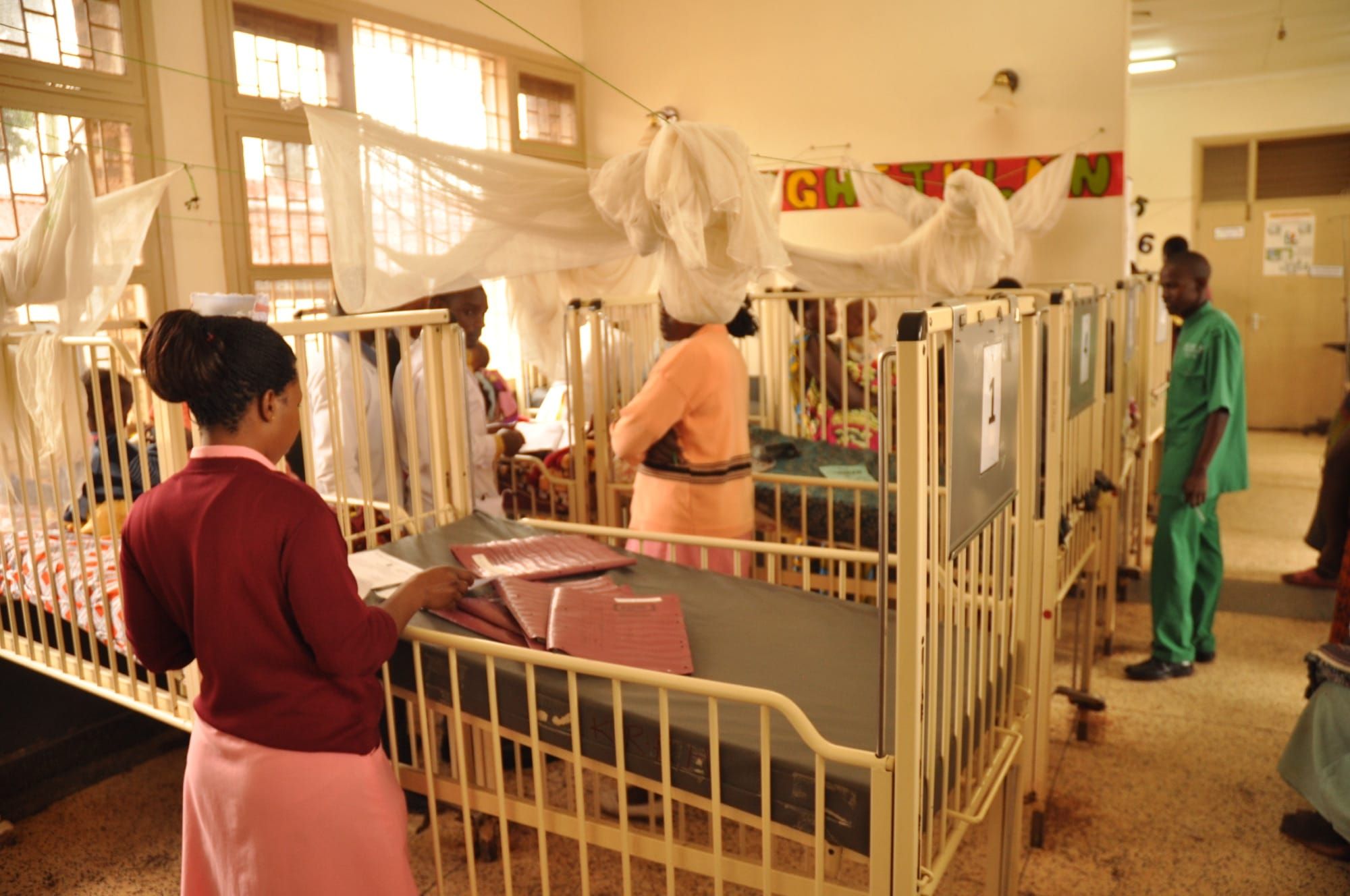 Interiorul unei secții de spital din Uganda, cu paturi pentru copii și personal medical