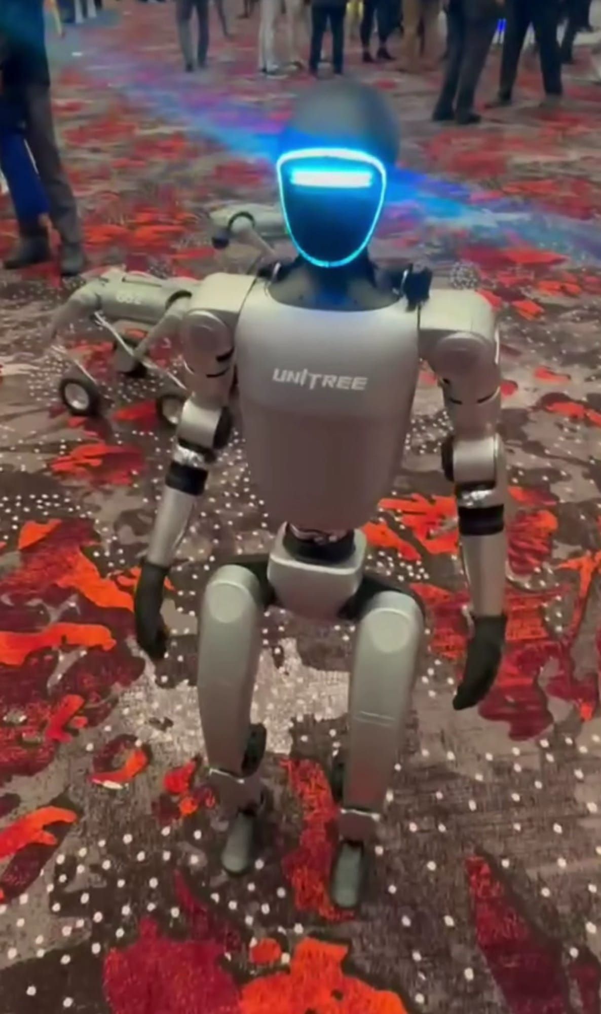 Robot umanoid Unitree, cu vizor luminos albastru, expus la un târg tehnologic