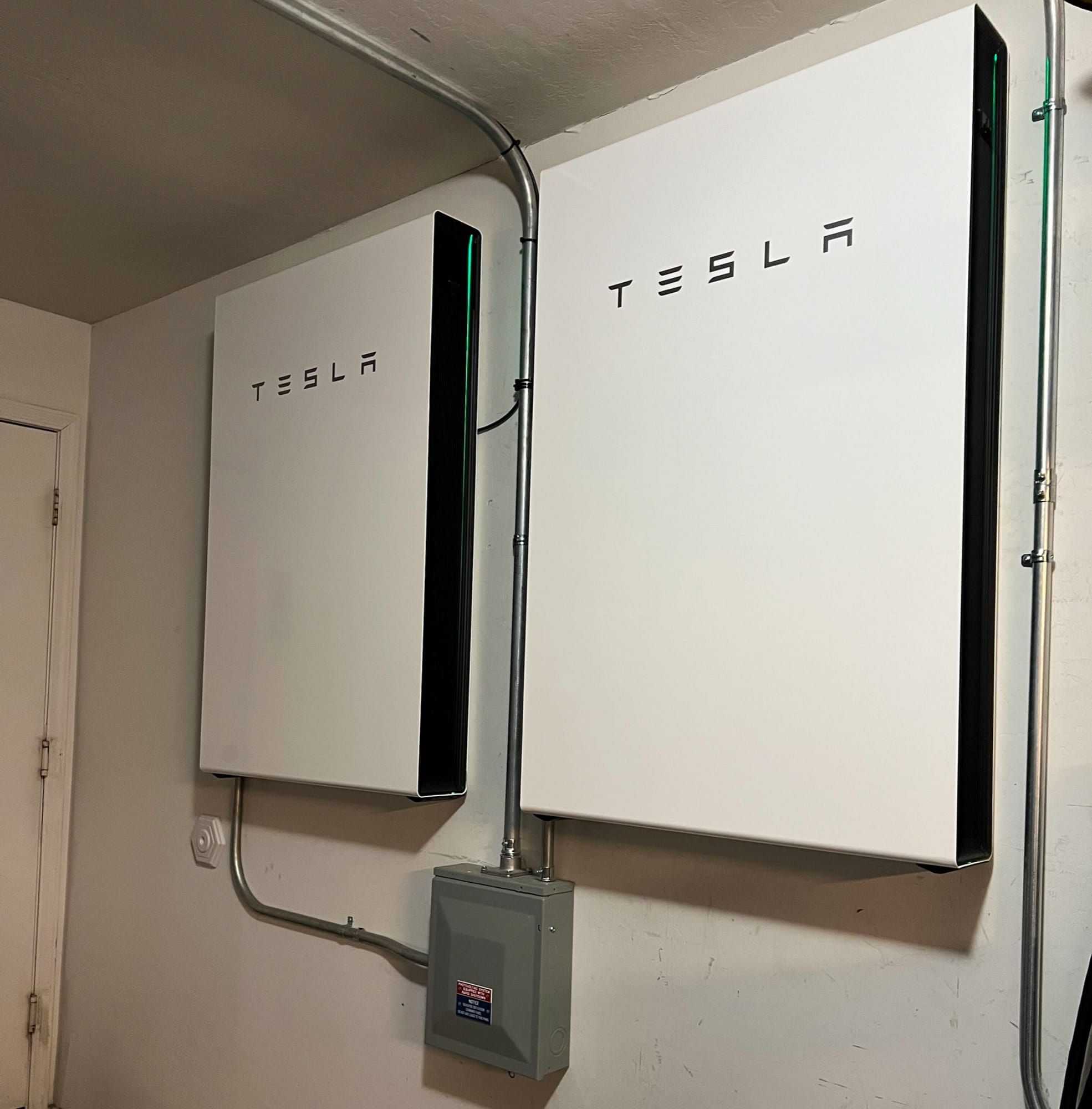 Două acumulatoare Tesla Powerwall 3 montate pe peretele unui garaj