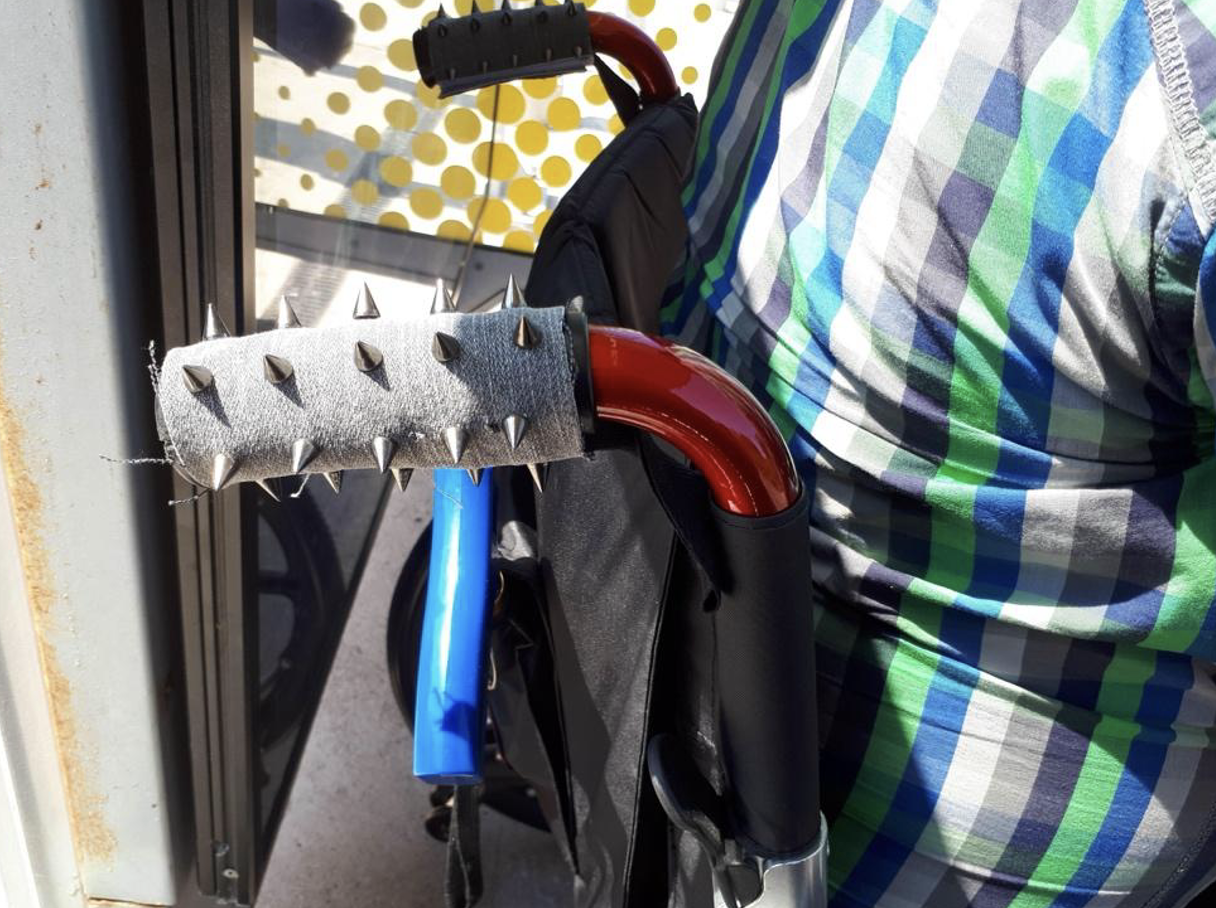 A manual wheelchair displays handles with punk-style spikes invented by John Farnworth
