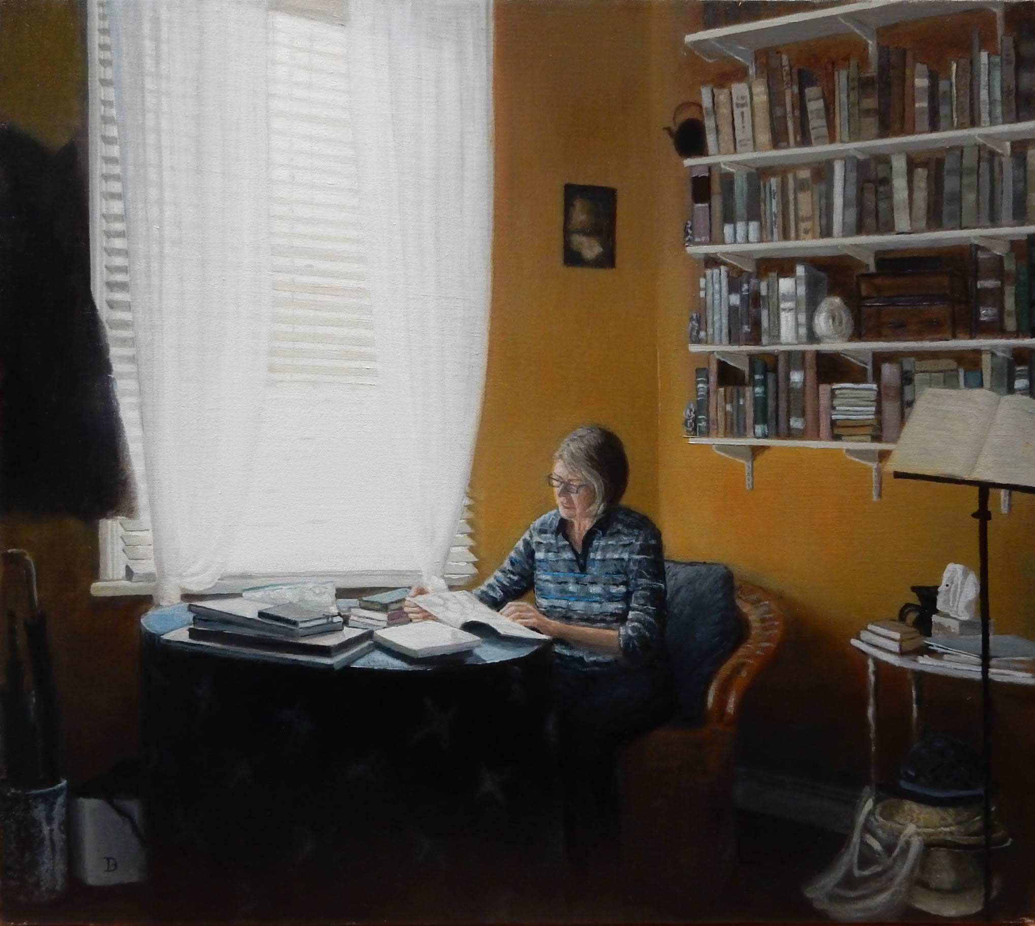 Jill sits at a table reading, next to a window. The walls are yellow. There are bookshelves. 
