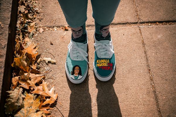 A shot of a person's feet with Kamala Harris painted on their trainers and RGB socks 
