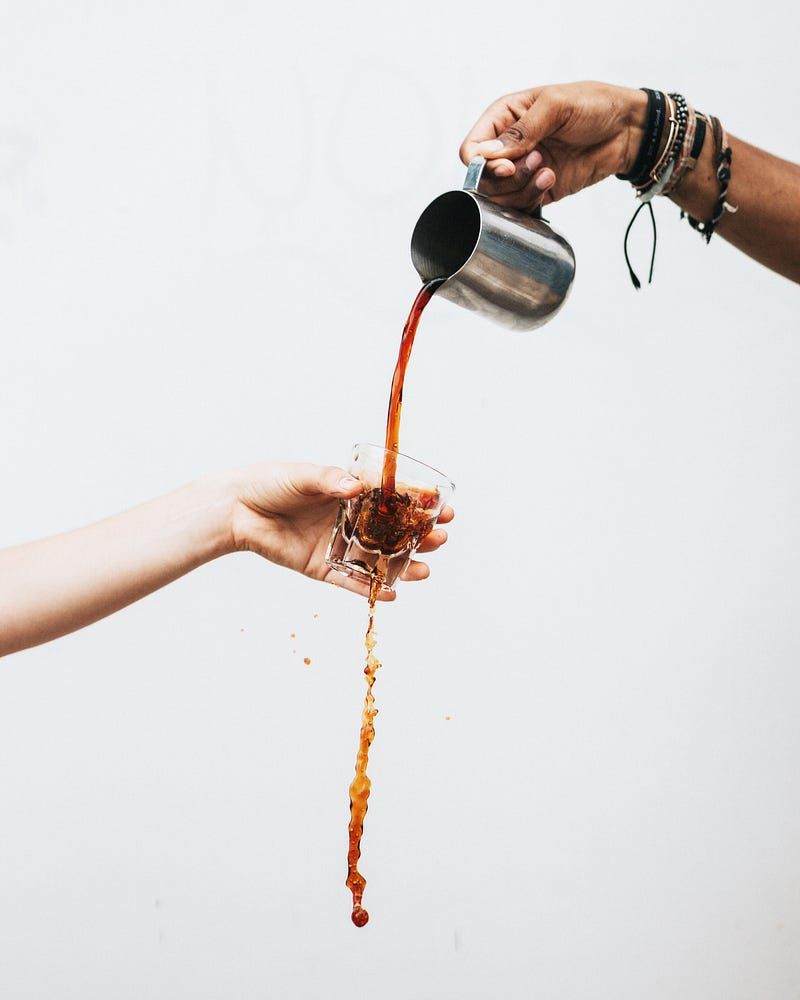 Pouring iced coffee through a cup.