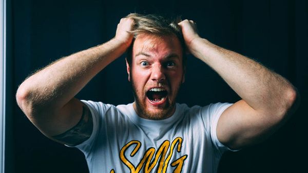Man in t-shirt pulling his hair out.