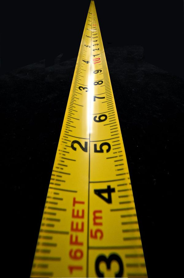 Yellow measuring tape on black background.