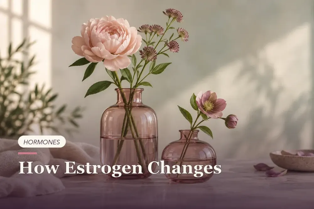 Rose-colored glass vessels with botanical stems at different heights.
