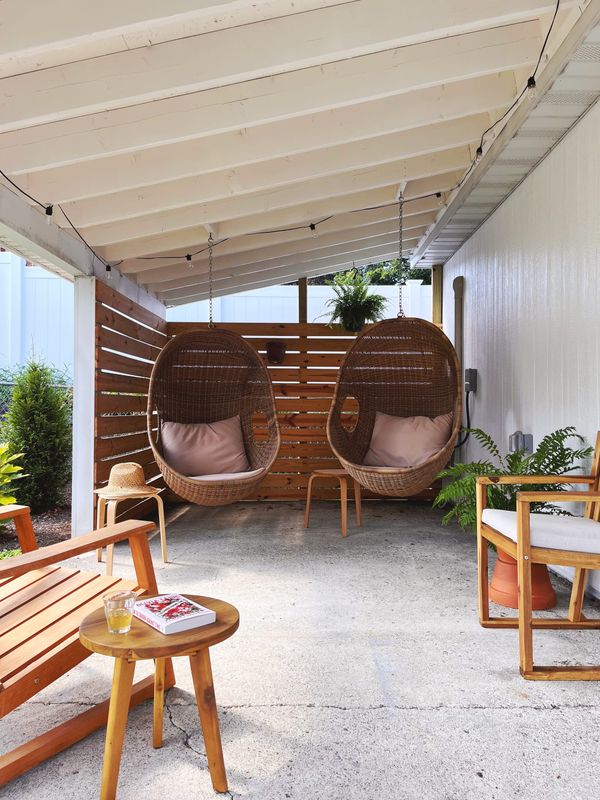 Carport converted to a covered porch with hanging chairs and ferns