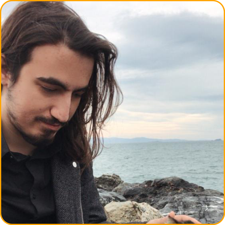 Ogulcan, a student from Turkey, is sitting on the shore by the ocean.