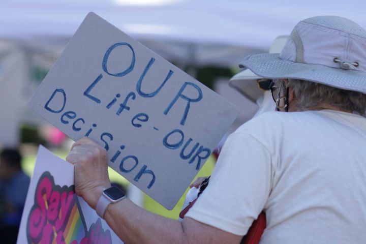 Man at a rally holding an "our life - our decision" sign