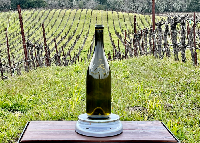 Logo bottle on scale with vineyard in background
