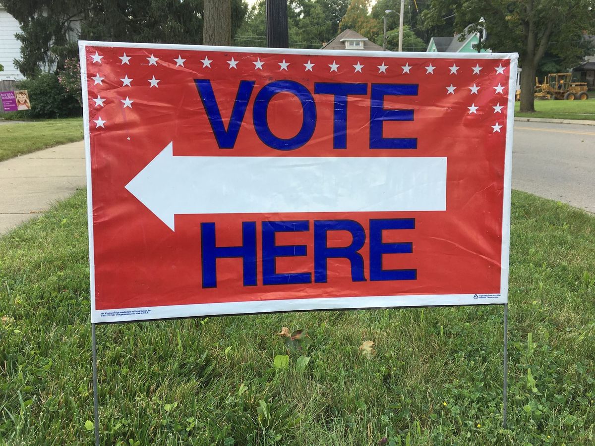 A "Vote Here" sign planted in the grass.