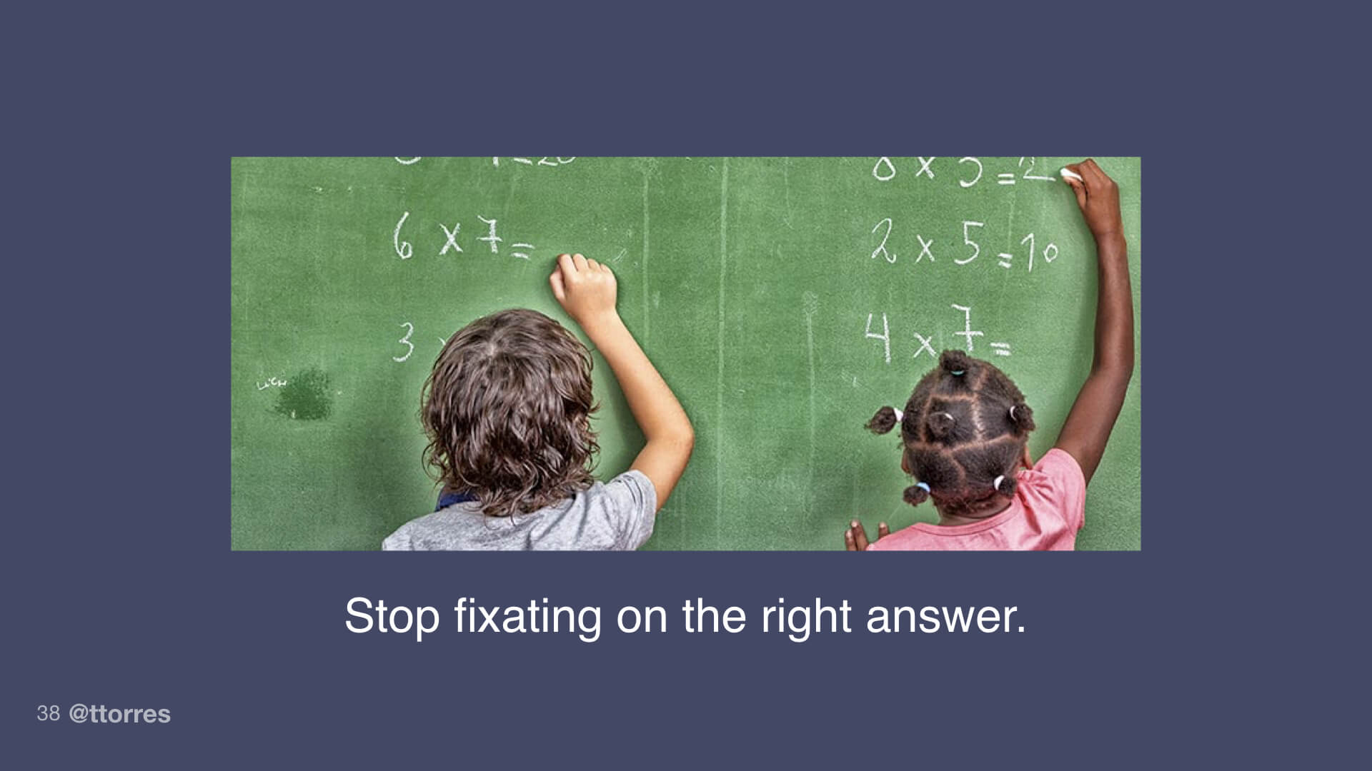 Two children performing multiplication problems on a chalkboard.