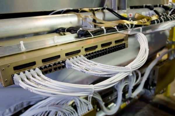 A close-up view of a network switch with multiple white Ethernet cables connected to its ports in a server rack.