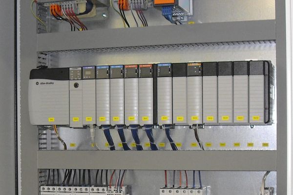 An Allen-Bradley ControlLogix PLC rack mounted inside an industrial electrical control cabinet with various I/O modules.