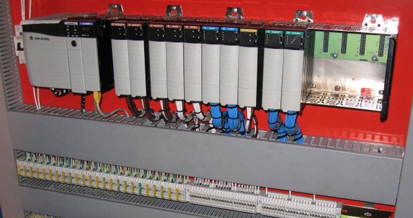 An Allen-Bradley MicroLogix 1100 programmable controller and 1762-series expansion modules mounted in a red control cabinet.