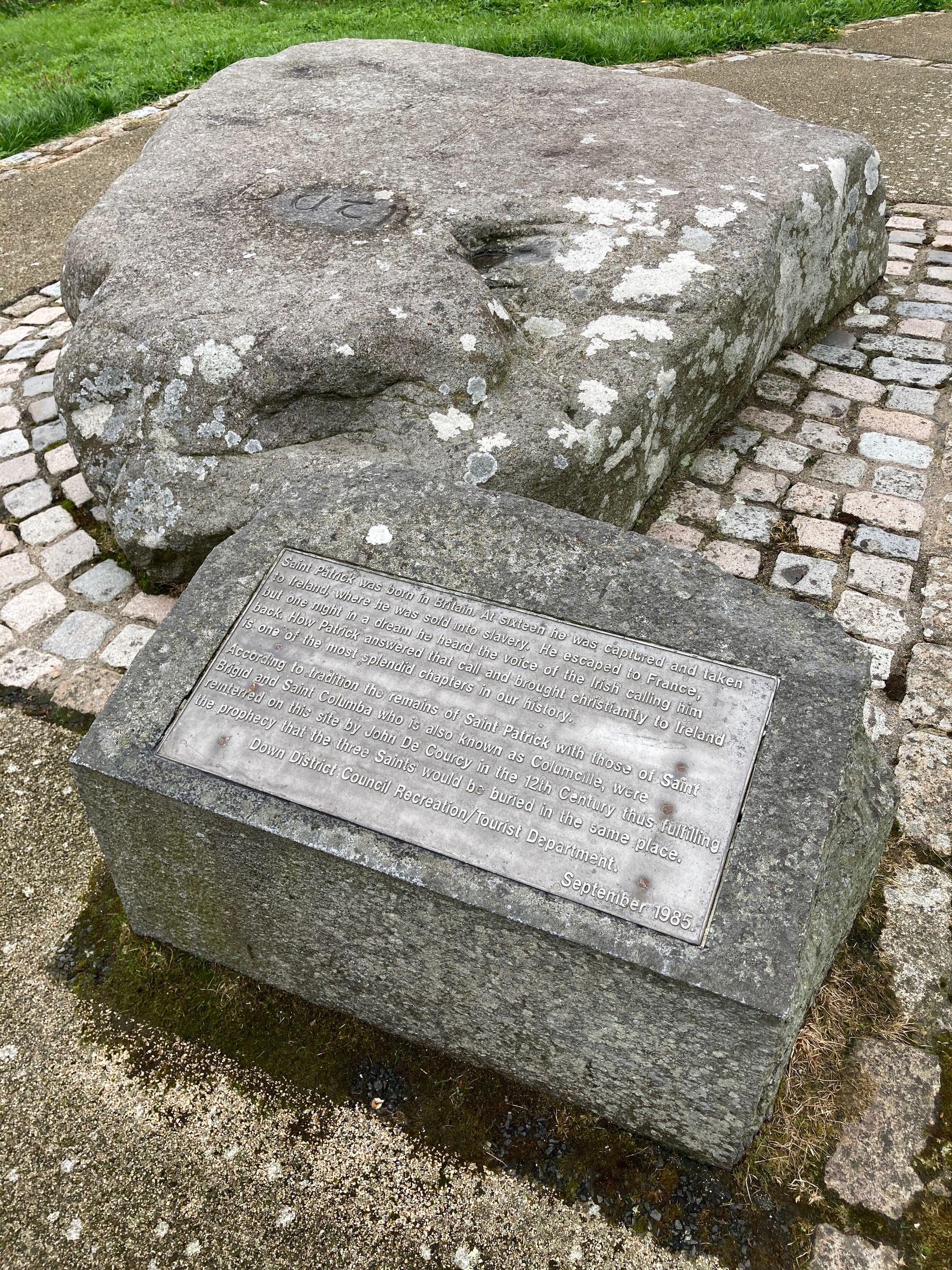 A large grey uneven rock with a plaque in front of it telling the story of St Patrick